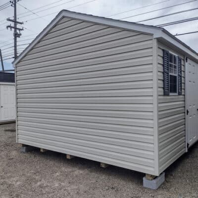 12x16 size vinyl a-roof style shed with almond siding, white trim, estate gray architectural shingle roof, gray shutters. has (1) 8' ridge vent, 6 foot fiber doors and two windows.