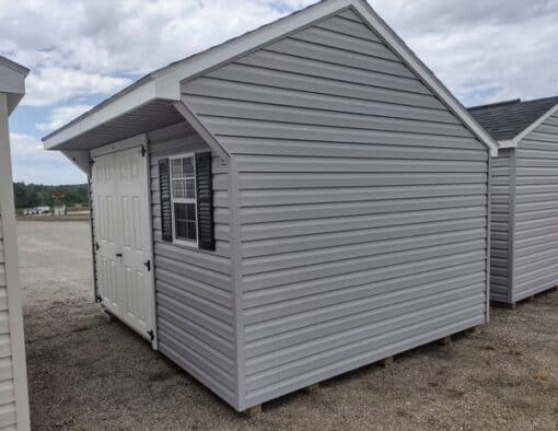 10x12 size vinyl carriage style shed with flint siding, white trim, black architectural shingle roof, black shutters. has (1) 8' ridge vent, 6 foot fiber doors and two windows.