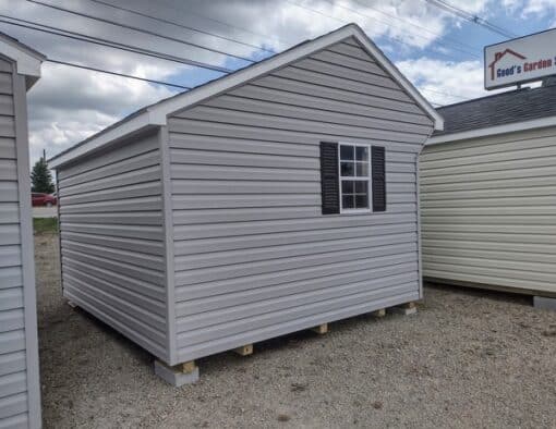 10x12 size vinyl carriage style shed with flint siding, white trim, black architectural shingle roof, black shutters. has (1) 8' ridge vent, 6 foot fiber doors and two windows.