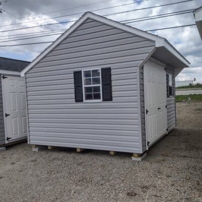 10x12 size vinyl carriage style shed with flint siding, white trim, black architectural shingle roof, black shutters. has (1) 8' ridge vent, 6 foot fiber doors and two windows.