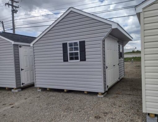 10x12 size vinyl carriage style shed with flint siding, white trim, black architectural shingle roof, black shutters. has (1) 8' ridge vent, 6 foot fiber doors and two windows.