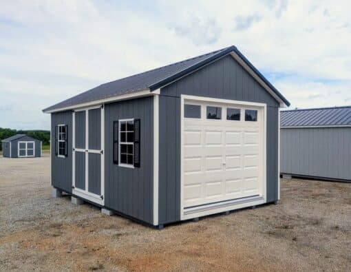 12 x 20 size painted classic garage style shed with gray siding, white trim, black metal roof, black shutters, garage door with glass, ggs 6 foot double doors 1' ft taller, two windows.