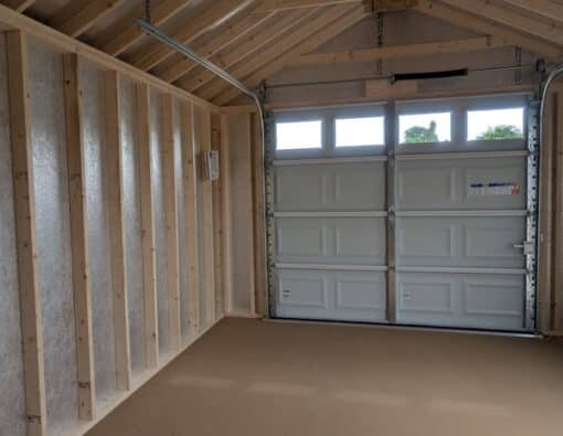 12 x 20 size painted classic garage style shed with gray siding, white trim, black metal roof, black shutters, garage door with glass, ggs 6 foot double doors 1' ft taller, two windows.