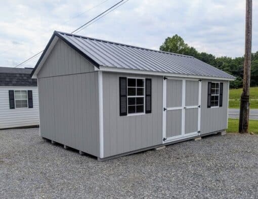 12 x 20 size painted classic style shed with gap gray siding, white trim, black metal roof, black shutters, ggs 6 foot doors, two windows.
