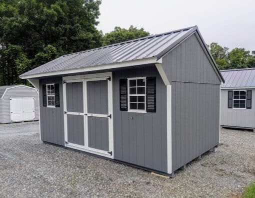 10 x 16 size painted carriage style shed with gray siding, white trim, black metal roof, black shutters, ggs 6 foot double doors, two windows.