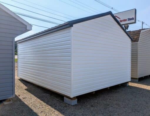 12x16 size vinyl a-roof style shed with white siding, black trim, black metal roof, black shutters. Has 6 foot fiber double doors and two windows.