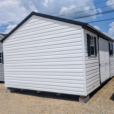 12x16 size vinyl a-roof style shed with white siding, black trim, black metal roof, black shutters. Has 6 foot fiber double doors and two windows.