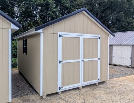 10 x 16 size painted classic style shed with tan siding, white trim, black metal roof, black shutters, ggs 6 foot double doors, two windows.