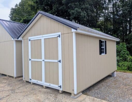 10 x 16 size painted classic style shed with tan siding, white trim, black metal roof, black shutters, ggs 6 foot double doors, two windows.