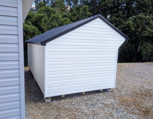 10x20 size vinyl carriage style shed with white siding, black trim, black metal roof, black shutters. Has 6 foot fiber 9 lite double doors and two windows and flower boxes.