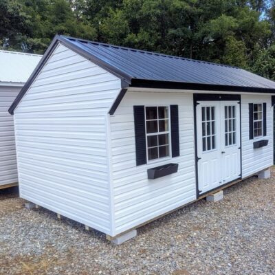10x20 size vinyl carriage style shed with white siding, black trim, black metal roof, black shutters. Has 6 foot fiber 9 lite double doors and two windows and flower boxes.
