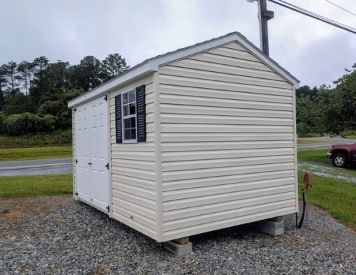 8x12 size vinyl a-roof style shed with pearl siding, white trim, black architectural shingle roof, black shutters. Has 8' ridge vent, 6 foot fiber double doors and one window.
