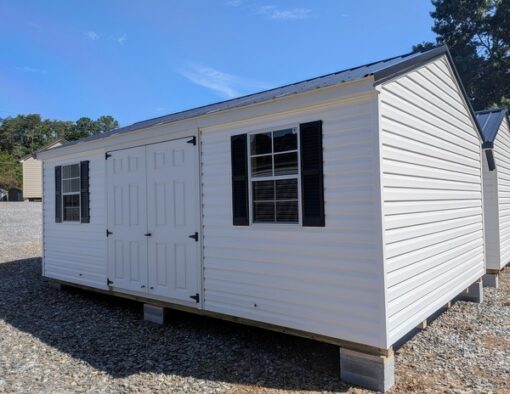 12x20 size vinyl a-roof style shed with white siding, white trim, black metal roof, black shutters. Has 6 foot fiber double doors and two windows.