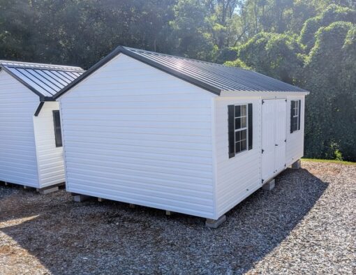 12x20 size vinyl a-roof style shed with white siding, white trim, black metal roof, black shutters. Has 6 foot fiber double doors and two windows.