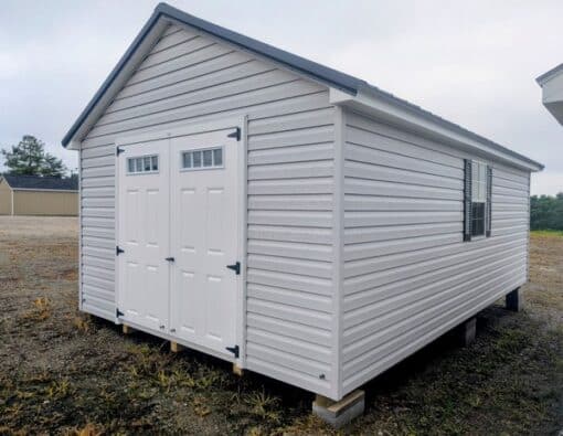 12 x 20 size vinyl classic style shed with gray siding, white trim, black metal roof, black shutters, fiber transom 6 foot double shed doors, two windows.