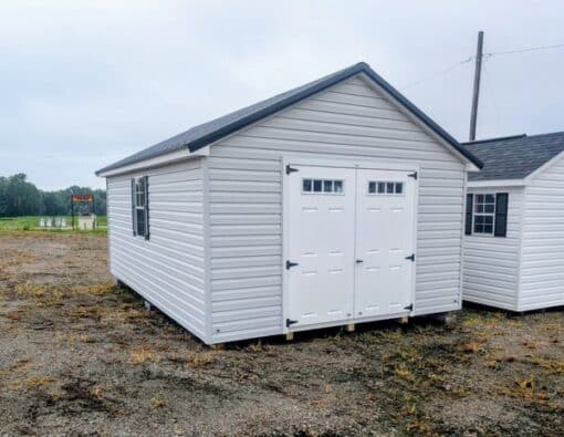 12 x 20 size vinyl classic style shed with gray siding, white trim, black metal roof, black shutters, fiber transom 6 foot double shed doors, two windows.
