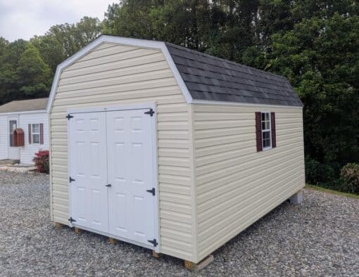 10x16 size vinyl high barn roof style shed with almond siding, white trim, black architectural shingle roof, burgundy shutters. has 8' ridge vent, 6 foot fiber double doors and two windows.