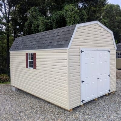 10x16 size vinyl high barn roof style shed with almond siding, white trim, black architectural shingle roof, burgundy shutters. has 8' ridge vent, 6 foot fiber double doors and two windows.