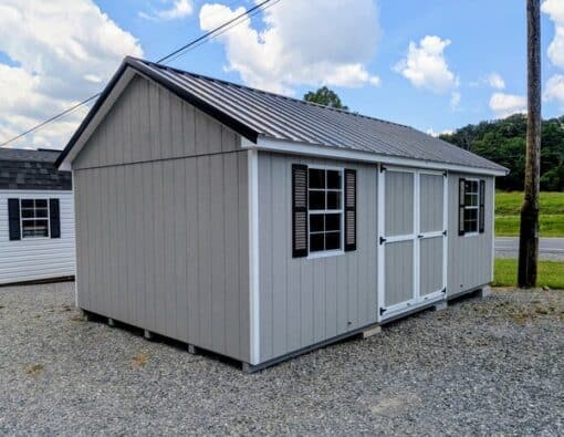 12 x 20 size painted classic style shed with gap gray siding, white trim, black metal roof, black shutters, ggs 6 foot doors, two windows.