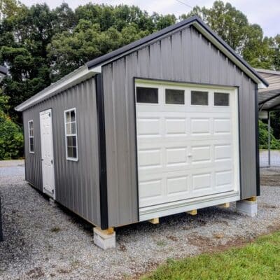 12x20 size metal classic garage style shed with white trim, charcoal metal siding, black metal roof, corners and j channel, 8x7 garage door with glass, 3 foot fiber solid shed door with two windows.