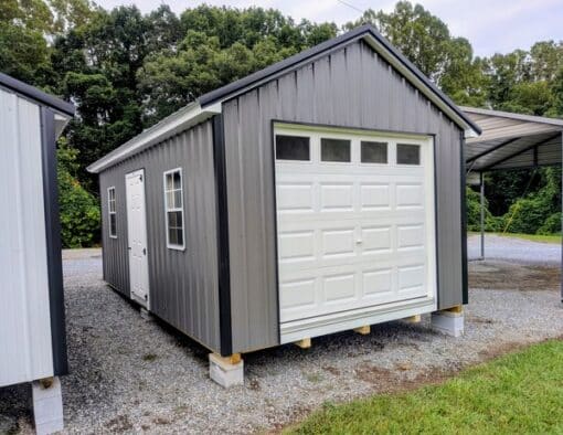 12x20 size metal classic garage style shed with white trim, charcoal metal siding, black metal roof, corners and j channel, 8x7 garage door with glass, 3 foot fiber solid shed door with two windows.