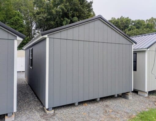 12 x 20 size painted a-roof style shed with gray siding, white trim, black metal roof, black shutters, ggs 6 foot double doors, two windows.