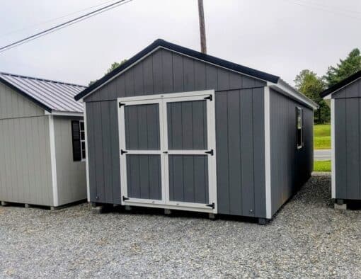 12 x 20 size painted a-roof style shed with gray siding, white trim, black metal roof, black shutters, ggs 6 foot double doors, two windows.