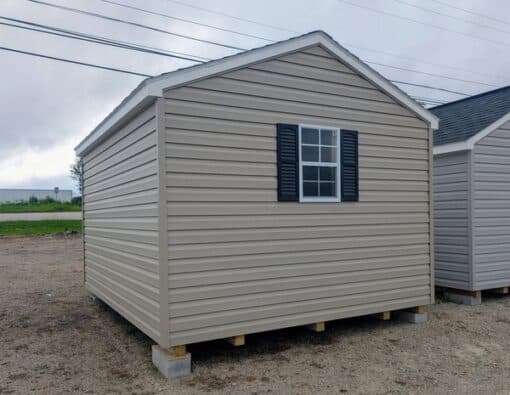 10x12 size vinyl a-roof style shed with clay siding, white trim, black architectural shingle roof, black shutters. has (1) 8' ridge vent, 6 foot fiber double doors and two windows.