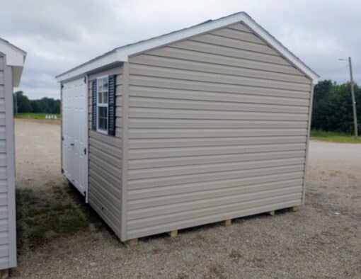 10x12 size vinyl a-roof style shed with clay siding, white trim, black architectural shingle roof, black shutters. has (1) 8' ridge vent, 6 foot fiber double doors and two windows.
