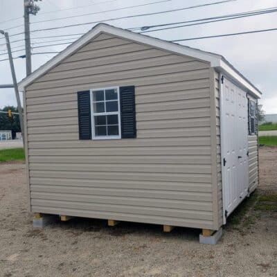 10x12 size vinyl a-roof style shed with clay siding, white trim, black architectural shingle roof, black shutters. has (1) 8' ridge vent, 6 foot fiber double doors and two windows.