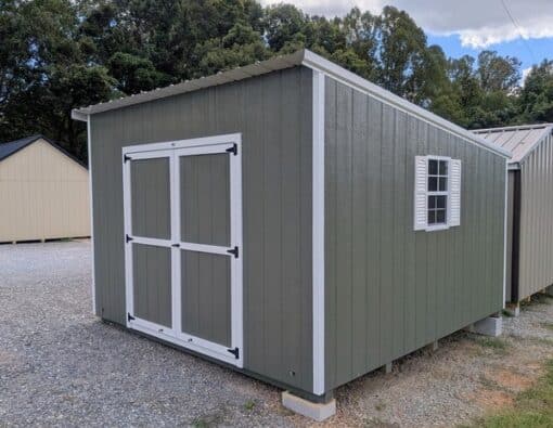 12x12 size painted economy style shed with avocado siding, white trim, alamo metal roof, white shutters, ggs 6 foot doors with two windows.