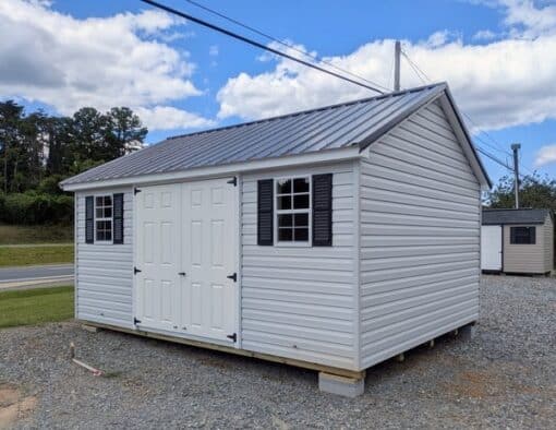 12 x 16 size vinyl classic style shed with gray siding, white trim, black metal roof, black shutters, fiber solid 6 foot double shed doors, two windows.