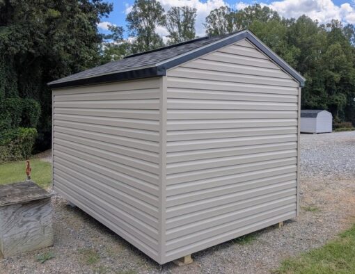 8x12 size vinyl a-roof style shed with clay siding, black trim, black architectural shingle roof, black shutters. Has 8' ridge vent, 6 foot fiber double doors and one black window.