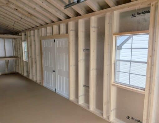 14 x 28 size vinyl a-roof garage style shed with clay siding, white trim, black metal roof, black shutters, 9x7 garage door, 6 foot fiber double doors with two windows.
