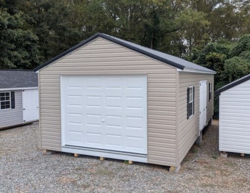 14 x 28 size vinyl a-roof garage style shed with clay siding, white trim, black metal roof, black shutters, 9x7 garage door, 6 foot fiber double doors with two windows.