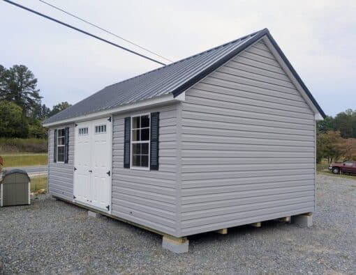 12 x 20 size vinyl garden style shed with flint siding, white trim, black metal roof, black shutters, fiber transom 6 foot double shed doors, two windows.