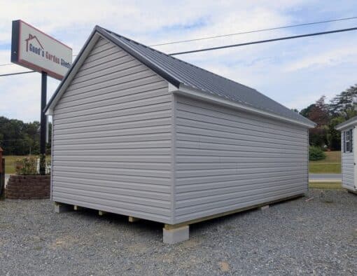 12 x 20 size vinyl garden style shed with flint siding, white trim, black metal roof, black shutters, fiber transom 6 foot double shed doors, two windows.