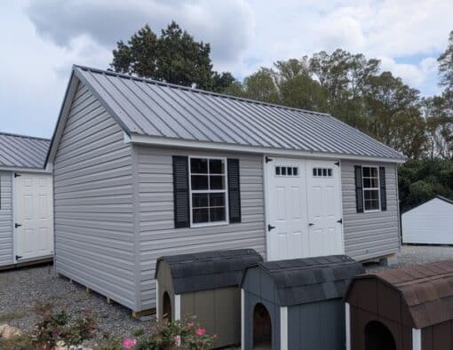 12 x 20 size vinyl garden style shed with flint siding, white trim, black metal roof, black shutters, fiber transom 6 foot double shed doors, two windows.