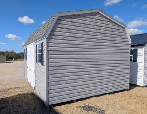 12x16 size vinyl high barn roof style shed with flint siding, white trim, estate gray architectural shingle roof, black shutters. has 8' ridge vent, 6 foot fiber double doors and two windows.