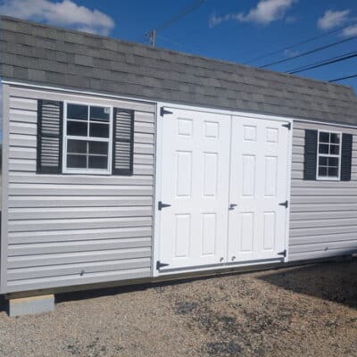 12x16 size vinyl high barn roof style shed with flint siding, white trim, estate gray architectural shingle roof, black shutters. has 8' ridge vent, 6 foot fiber double doors and two windows.