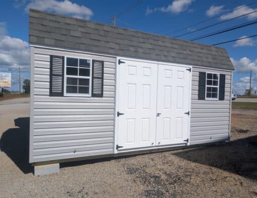 12x16 size vinyl high barn roof style shed with flint siding, white trim, estate gray architectural shingle roof, black shutters. has 8' ridge vent, 6 foot fiber double doors and two windows.