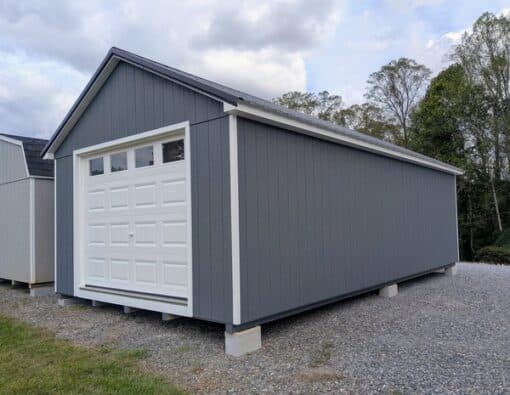 14 x 28 size painted classic garage style shed with gray siding, white trim, black metal roof, black shutters, garage door with glass, ggs 6 foot double doors 1' ft taller, two windows.
