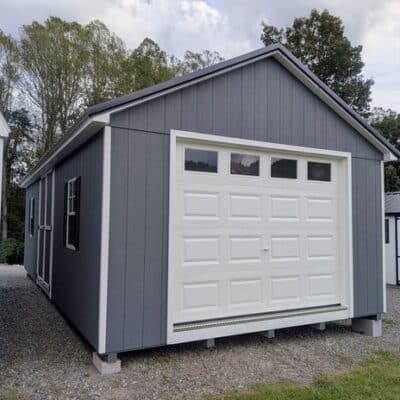 14 x 28 size painted classic garage style shed with gray siding, white trim, black metal roof, black shutters, garage door with glass, ggs 6 foot double doors 1' ft taller, two windows.