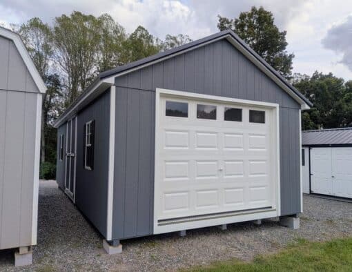 14 x 28 size painted classic garage style shed with gray siding, white trim, black metal roof, black shutters, garage door with glass, ggs 6 foot double doors 1' ft taller, two windows.