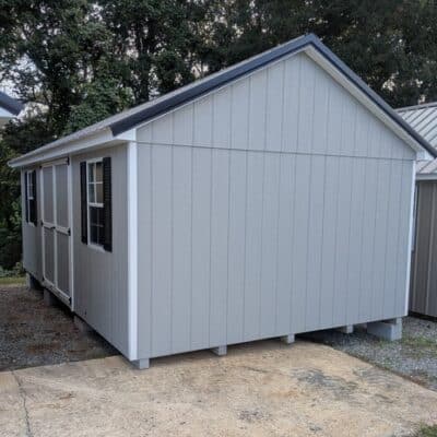 12 x 20 size painted classic style shed with gap gray siding, white trim, black metal roof, black shutters, ggs 6 foot doors, two windows.