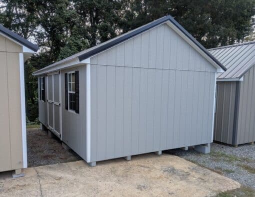 12 x 20 size painted classic style shed with gap gray siding, white trim, black metal roof, black shutters, ggs 6 foot doors, two windows.