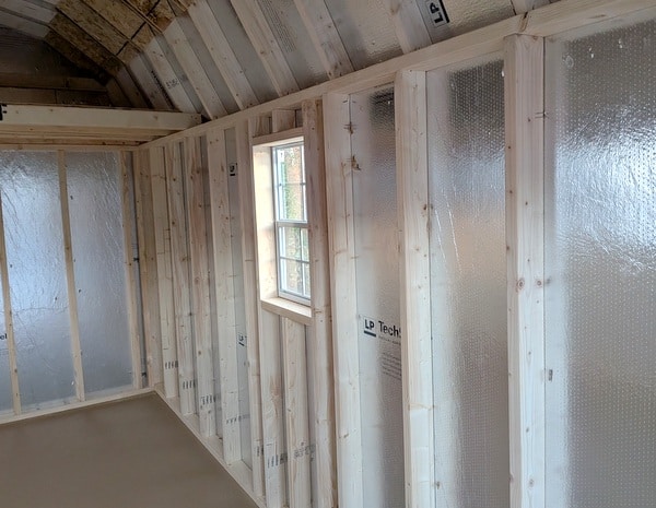 10x16 size vinyl high barn roof style shed with clay siding, white trim, black architectural shingle roof, black shutters. has 8' ridge vent, 6 foot fiber double doors and two windows.