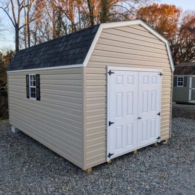 10x16 size vinyl high barn roof style shed with clay siding, white trim, black architectural shingle roof, black shutters. has 8' ridge vent, 6 foot fiber double doors and two windows.