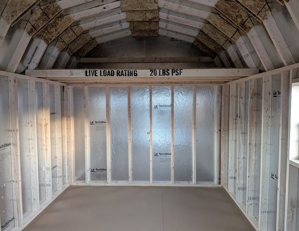 10x16 size vinyl high barn roof style shed with clay siding, white trim, black architectural shingle roof, black shutters. has 8' ridge vent, 6 foot fiber double doors and two windows.