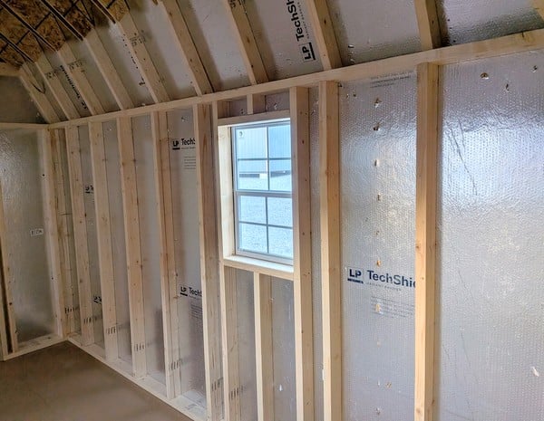 10x16 size vinyl high barn roof style shed with clay siding, white trim, black architectural shingle roof, black shutters. has 8' ridge vent, 6 foot fiber double doors and two windows.